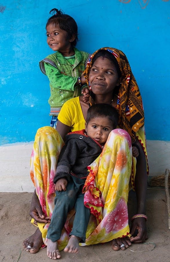 A woman sits on the ground with two children